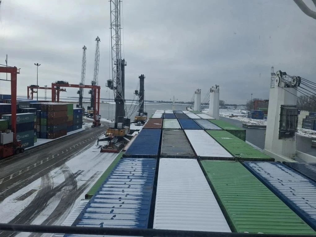 Контейнеры на заснеженной палубе у портового терминала